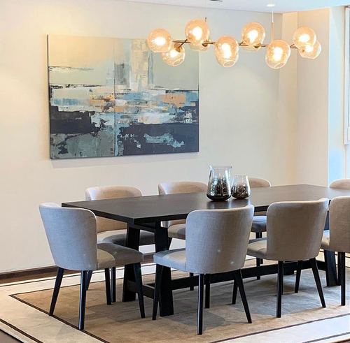 Dining room with dark wood table, grey upholstered chairs, globe chandelier, and abstract painting