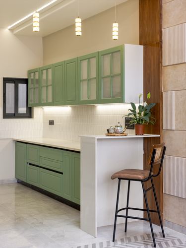 Sage green kitchen with glass cabinets and white breakfast counter with bar stool