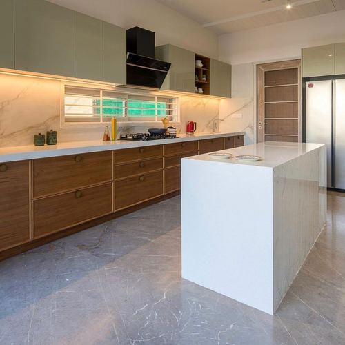 Modern kitchen with sage cabinets, wood drawer run, stone backsplash, and white waterfall island.