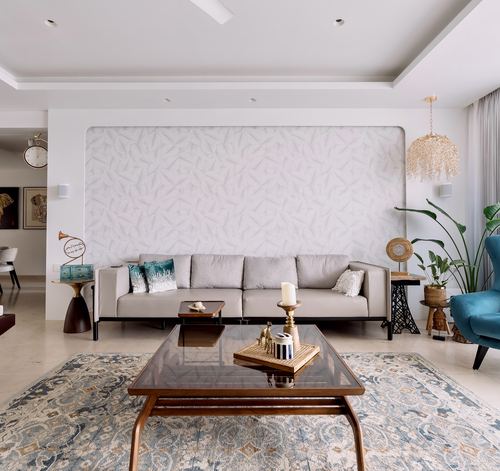 Neutral living room with beige sofa, textured wall panel, glass coffee table and patterned rug