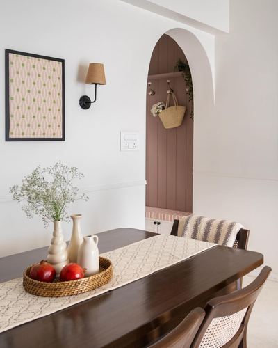 Dining table with pomegranates and vases beside an arched terracotta niche seat