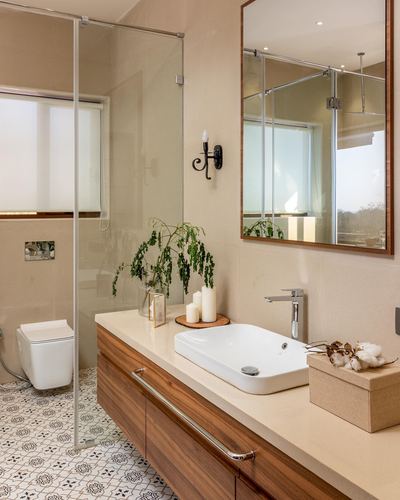 Bathroom vanity with wood cabinetry, vessel sink, framed mirror and patterned floor tile