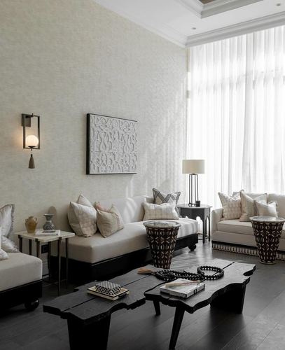 Neutral living room with sheer curtains, black live-edge coffee table, and carved Moroccan side stools