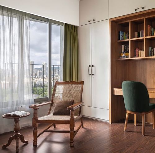 Cane armchair by window with city view, wooden study desk and bookshelf beyond
