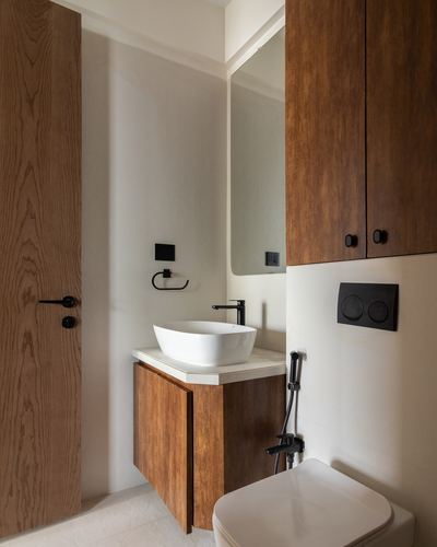 Small bathroom with wood cabinetry, white vessel sink, black fixtures, and wood-panelled door