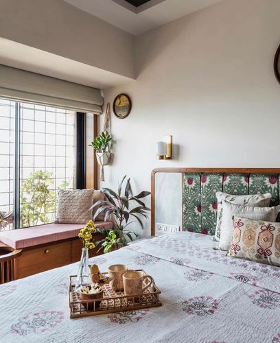 Bedroom corner with floral upholstered headboard, wooden window seat, and breakfast tray on bed