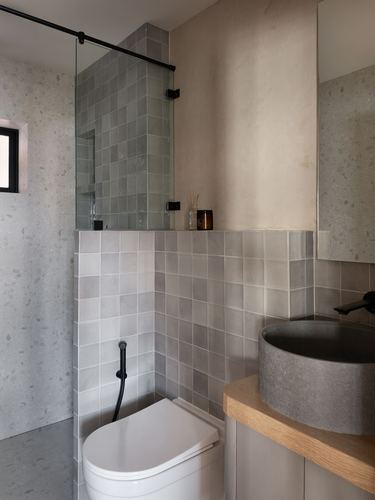 Bathroom with sage zellige tile shower, terrazzo walls, concrete vessel sink and wooden vanity