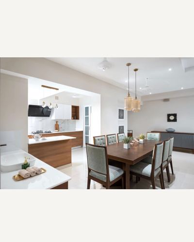 Open-plan dining area with wooden table, pendant lights, visible kitchen and vanity beyond
