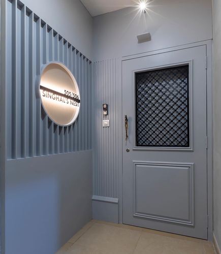 Blue-grey fluted panelled entrance with backlit nameplate niche and patterned-glass front door