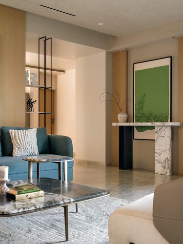 Living room with teal sofa, marble console table, and green abstract artwork on wood wall