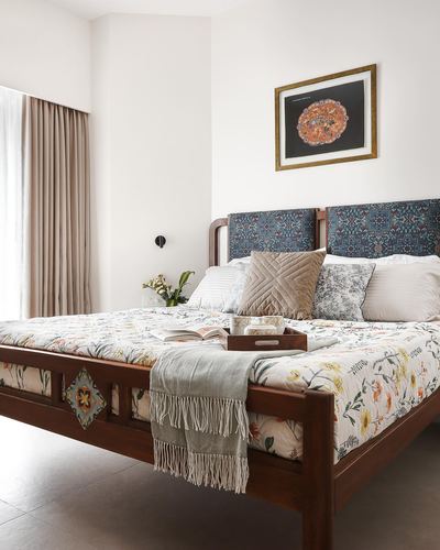 Bedroom with carved wood bed, floral bedding, blue patterned headboard, and framed art above