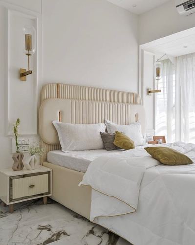 Beige tufted headboard bedroom with brass sconces and marble floor in Mumbai home