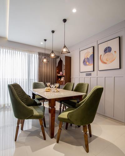 Dining room with marble-top table, green velvet chairs, and geometric pendant lights