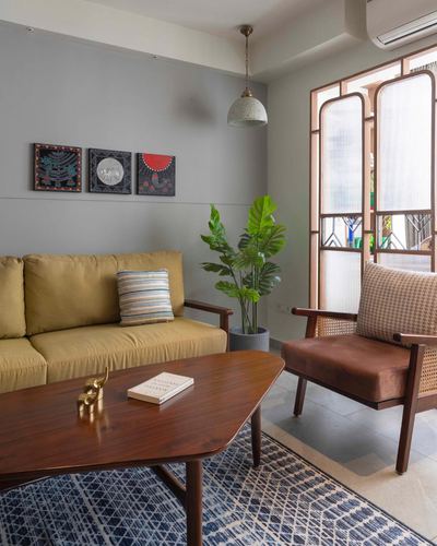 Living room with mustard sofa, cane armchair, wooden coffee table and arched window