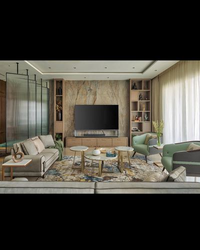 Living room with stone feature wall, TV, round nesting tables and sage armchairs