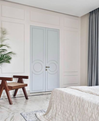 Bedroom corner with panelled wall, blue-grey double doors, cane chair, and marble floor