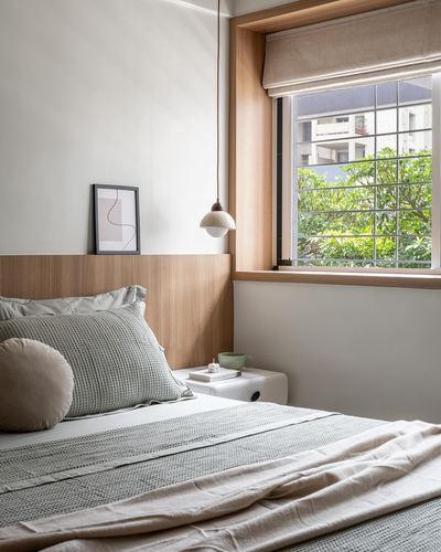 Japandi-style bedroom with wood headboard wall, pendant light, and window overlooking greenery