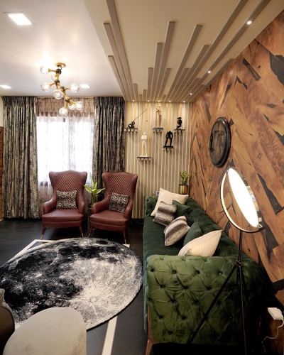 Living room with green tufted sofa, leather wingback chairs, chevron wood wall and round moon rug
