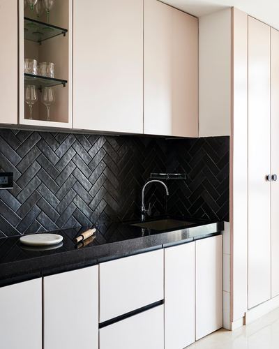 Kitchen corner with black herringbone tile backsplash, black countertop, and blush pink cabinetry