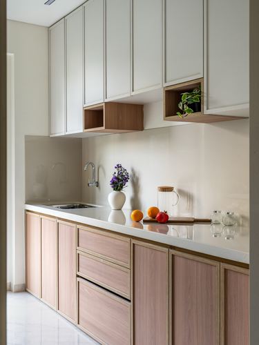 Galley kitchen with white upper cabinets, blush wood lower cabinets, and open display niches over the counter.