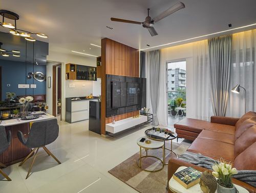 Open-plan living and dining room with wood tv column, leather sofa and balcony view at dusk