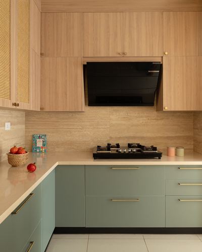Corner kitchen with wood upper cabinets, sage green lower units, stone backsplash and black hob