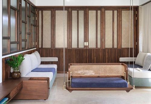 Living room with a cane-backed wooden swing, cane wall panels, and a cream corner sofa