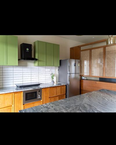 Kitchen with olive green cabinets, wood cabinetry, cane-front unit, and marble-look island counter