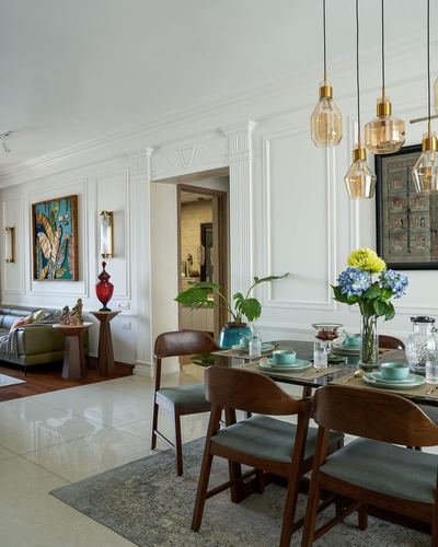 Dining area with wood chairs, amber pendant lights, and classical wall paneling opening to living room