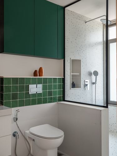 Bathroom with green tiled wall, green wall cabinets, and terrazzo-walled glass shower stall