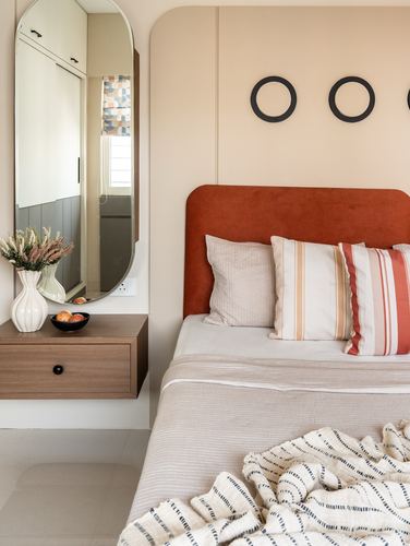 Bedroom with terracotta headboard, floating wood nightstand, and tall oval mirror
