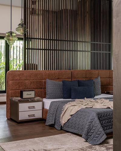 Bedroom with tan leather headboard, navy pillows, wood slat screen and marble-top nightstand