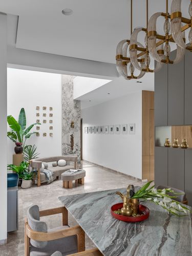Open-plan dining and living view through marble corridor with brass chandelier and gallery wall