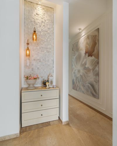Foyer niche with textured tile wall, hanging pendant lights, and cream chest of drawers beside hallway