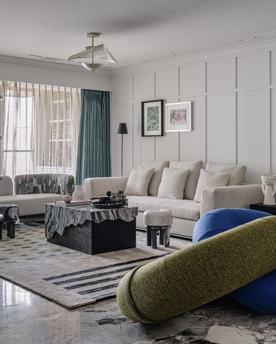 Living room with beige sofa, marble coffee table, and olive-blue bolster cushions in foreground