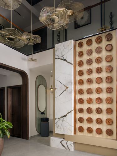 Foyer with marble column, wooden carved disc wall, and wire pendant lights