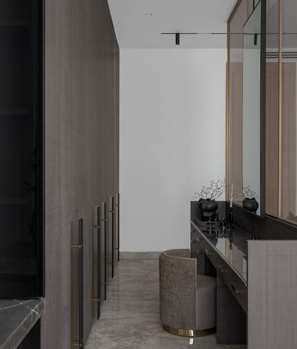 Dressing corridor with wood-panelled wardrobes leading to a mirrored vanity and round stool