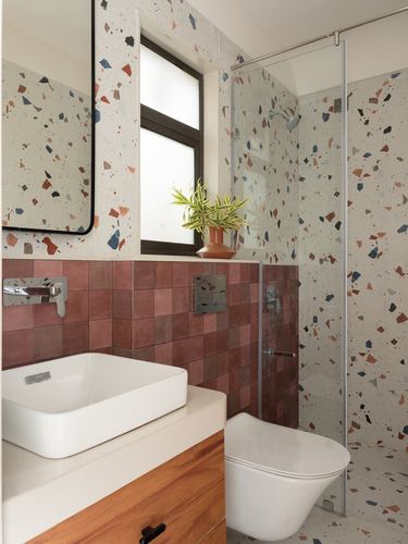 Bathroom with terrazzo walls, pink tiled dado, wall-hung toilet and wooden vanity with vessel sink