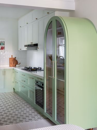 Sage green kitchen with arched glass pantry cabinet and patterned star floor tiles