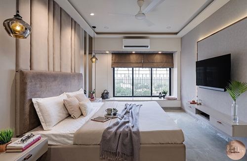 Neutral-toned bedroom with upholstered headboard, window seat, pendant lights and wall-mounted tv