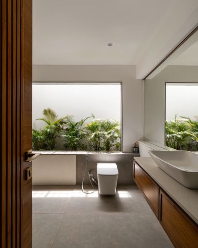 Modern bathroom with wooden vanity, vessel sink, and window strip showing indoor plants