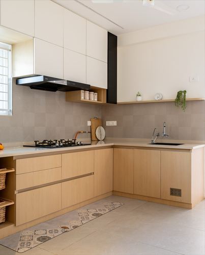L-shaped modern kitchen with light wood cabinetry, textured grey backsplash, and black chimney hood