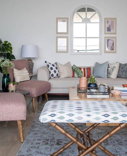 Living room with pink armchair, patterned cushions, arched window and gallery wall above beige sofa