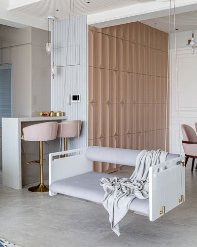 Suspended white acrylic daybed swing with grey throw in front of a scalloped blush wall panel