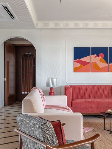 Living room with pink velvet sofa, cream armchairs, and a desert-toned triptych painting