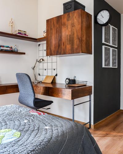 Study nook with floating wood desk, wire pinboard, wall clock and dark accent wall