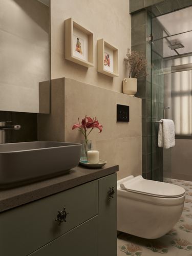 Bathroom with vessel sink, green vanity, wall-hung toilet, patterned floor and framed art niche