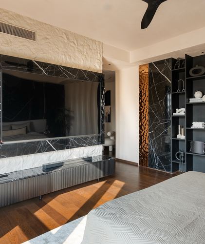 Bedroom with black marble TV wall, textured stone panel, dark wood floor and open shelving unit