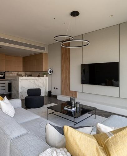 Open-plan living room with grey sofa, mustard cushions, marble kitchen island and ring pendant lights