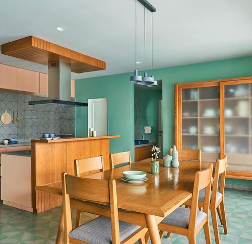 Teal-walled dining and kitchen with wooden table, chairs, and geometric tile floor